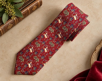 May include: A red necktie featuring a repeating pattern of white unicorns and small blue and green floral motifs. The fabric has a smooth texture and the tie is shown laid flat, displaying the pointed tip and the folded upper section.