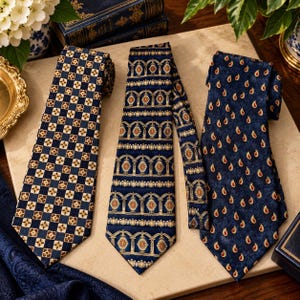 May include: Three neckties displayed side by side. The left tie features a navy blue and gold checkered pattern with small floral centers. The center tie has a navy blue background with gold arched columns and red accents. The right tie is navy blue with a gold paisley print.