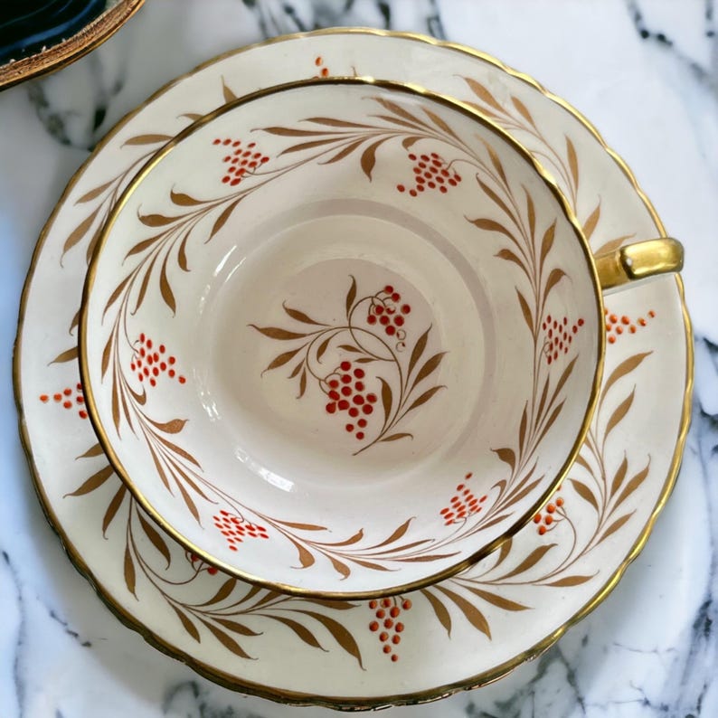 Pu&ograve; includere: Servizio da t&egrave; color crema con bordo e manico dorati. Il set presenta un design a bacche e foglie marroni e rosse. La tazza da t&egrave; poggia sul piattino abbinato, creando un look classico ed elegante.