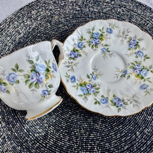 Pu&ograve; includere: Una tazza da t&egrave; e un piattino bianchi con un motivo floreale blu e bianco. La tazza e il piattino hanno un bordo dorato.