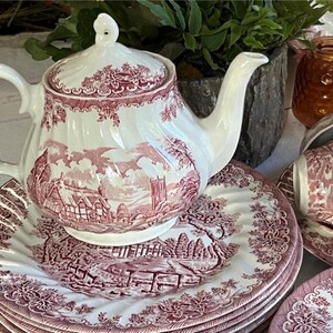 Pu&ograve; includere: Un servizio da t&egrave; bianco e bordeaux con teiera, piatti e tazze da t&egrave;. Il set presenta un design paesaggistico dettagliato. La teiera &egrave; sopra una pila di piatti. Le tazze da t&egrave; sono su piattini. Il set &egrave; in ceramica.