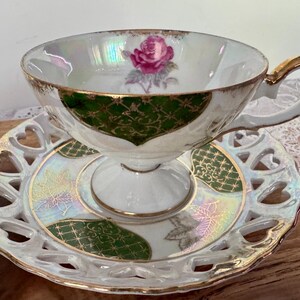 Puede incluir: Un juego de taza y platillo de t&eacute; vintage. La taza blanca presenta un dise&ntilde;o de rosa rosa y ribetes dorados. El platillo tiene un borde en forma de coraz&oacute;n y detalles en verde y dorado. El juego est&aacute; dise&ntilde;ado para tomar el t&eacute; y ocasiones especiales.