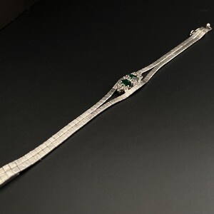 May include: A silver chain bracelet with a green stone set in a silver frame.