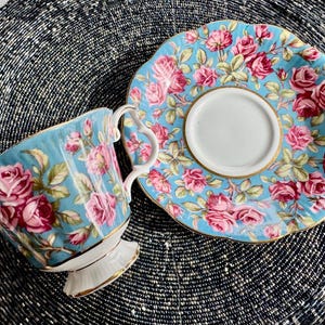 K&ouml;nnte beinhalten: Ein blaues und wei&szlig;es Tee-Set mit einem floralen Muster aus rosa Rosen. Das Set ist aus feinem Porzellan gefertigt und hat ein zartes Design.