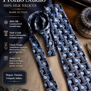 Puede incluir: Una corbata de seda azul marino con un patr&oacute;n geom&eacute;trico repetitivo de motivos florales en azul claro y gris. La corbata muestra un tejido texturizado y se presenta junto al texto Vintage Profilo Studio 100% SILK NECKTIE MADE IN ITALY.