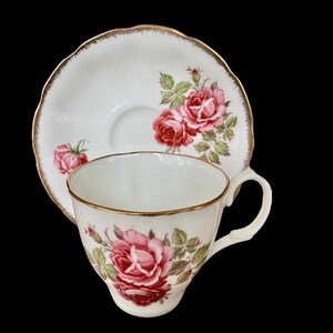 Pu&ograve; includere: Un set da t&egrave; bianco con bordo dorato e un motivo floreale con rose rosa e foglie verdi.