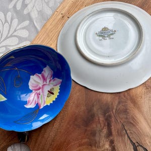 Puede incluir: Un juego de taza y platillo de t&eacute; azul y blanco con un dise&ntilde;o floral. El platillo tiene un borde dorado y el texto "Princess China Made in Japan" en la parte inferior.