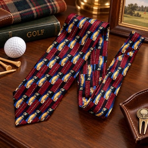 May include: A necktie featuring a repeating pattern of yellow golf bags on blue squares, separated by vertical stripes of textured dark red fabric. The tie displays a consistent graphic print of golf equipment across its entire length.