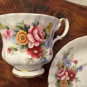 May include: A white teacup and saucer set with a floral pattern. The cup has a gold rim and a delicate handle. The saucer has a matching floral design.