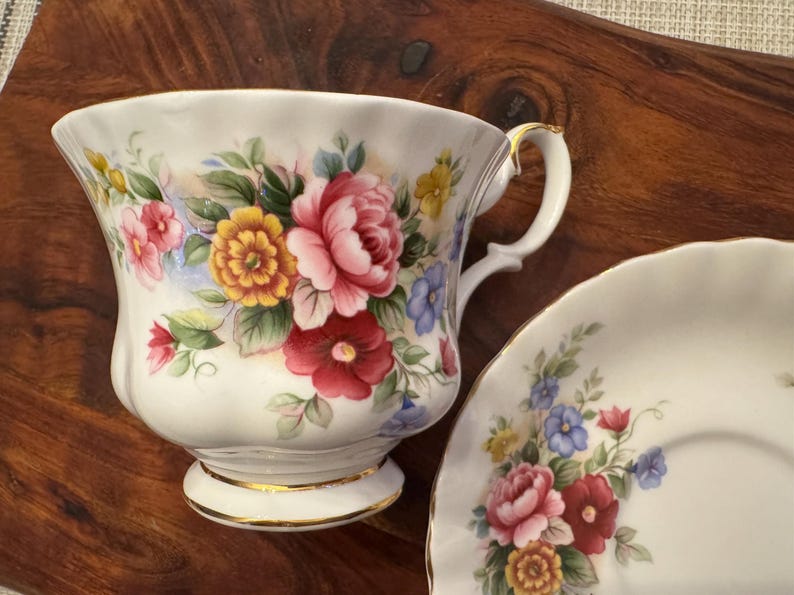 May include: A white teacup and saucer set with a floral pattern. The cup has a gold rim and a delicate handle. The saucer has a matching floral design.