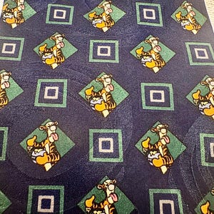 K&ouml;nnte beinhalten: Marineblaue Krawatte mit einem sich wiederholenden Muster der Figur Tigger aus Winnie Puuh. Das Design umfasst Tigger in einer Raute, umgeben von gr&uuml;nen Rauten und blauen Quadraten. Die Krawatte ist aus glattem Material, m&ouml;glicherweise Seide.