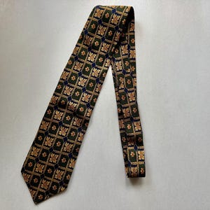May include: A necktie featuring a dark green background with a repeating grid pattern. Each square in the grid contains a gold-colored floral motif and is separated by small, dark blue diamond shapes at the intersections of the grid lines.