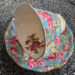 K&ouml;nnte beinhalten: Ein Vintage-Teetassen- und Untertassen-Set mit einem blauen und wei&szlig;en Blumenmuster. Die Tasse hat einen goldenen Rand und die Untertasse einen gewellten Rand.
