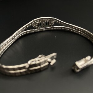 May include: A silver bracelet with a triple row chain design. The bracelet has a clasp closure and features the word "XOXO" in the centre.