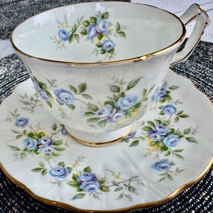 Pu&ograve; includere: Un set da t&egrave; bianco con un motivo floreale blu e verde. La tazza e il piattino hanno un bordo dorato.