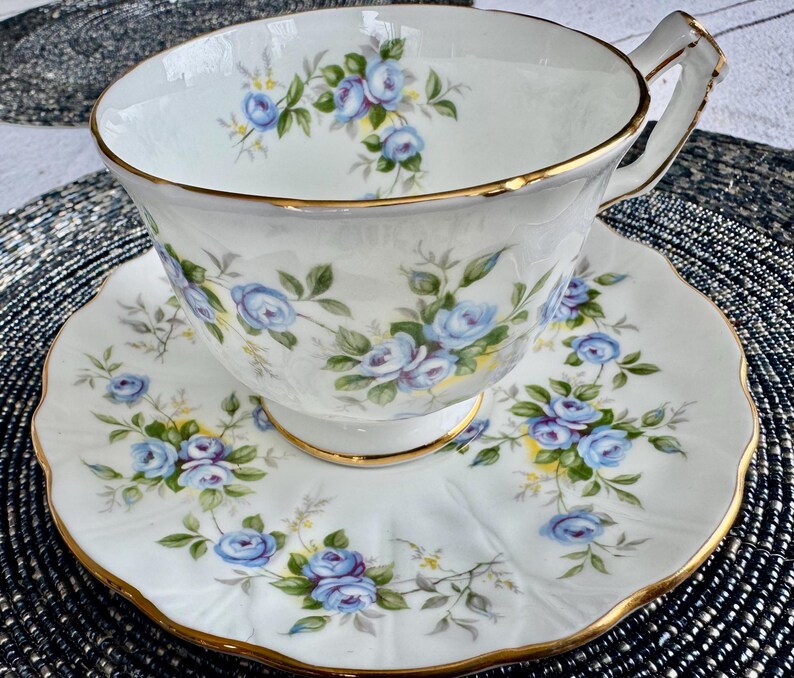 Pu&ograve; includere: Un set da t&egrave; bianco con un motivo floreale blu e verde. La tazza e il piattino hanno un bordo dorato.