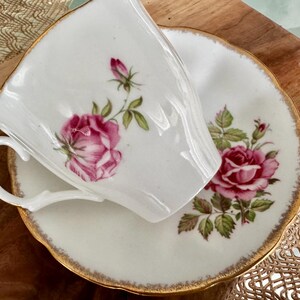 Pu&ograve; includere: Un set da t&egrave; bianco con bordo dorato. Il set presenta un motivo floreale con rose rosa e foglie verdi.