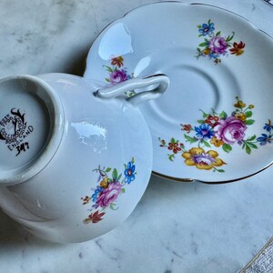 Puede incluir: Juego de taza y platillo blancos con dise&ntilde;os florales en rosa, azul, amarillo y rojo. La taza tiene un asa curvada y un dise&ntilde;o en espiral. El platillo tiene un borde dorado. La taza tiene el texto "EST 1790 COLLINGWOOD BONE CHINA ENGLAND 347".