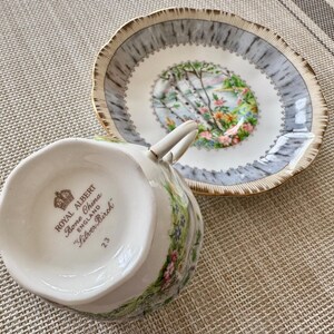 Pu&ograve; includere: Una tazzina da t&egrave; e un piattino bianchi con un motivo floreale. Il piattino ha un design di betulla argentata con un bordo dorato. La tazzina da t&egrave; ha le parole "Royal Albert Bone China England "Silver Birch" 23" sul fondo.