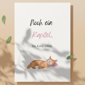 May include: A white card with the text "Noch ein Kapitel" in black and "Kapitel" in pink. Below, the text "Die Katze schläft." is written in black. A watercolor illustration of a sleeping orange cat on a pink pillow is at the bottom.