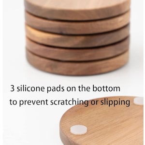 May include: A set of six round wooden coasters with a natural wood finish. The coasters have three silicone pads on the bottom to prevent scratching or slipping.