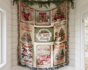 May include: A Christmas-themed tapestry with various vintage-style signs. The signs feature images of a hot chocolate bar, a village shop, a Christmas tree on a wagon, a bed and breakfast, a snowman, and the text "The Smith Family".