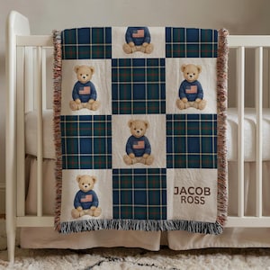 May include: A baby blanket with a plaid pattern in navy blue, green, and red. The blanket features squares with teddy bears wearing sweaters with an American flag design. The name "JACOB ROSS" is printed on the blanket.