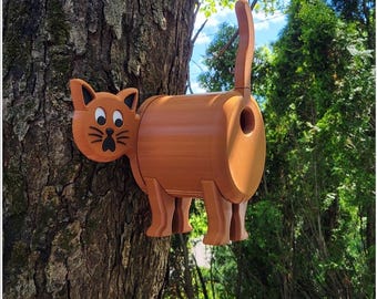 May include: A brown wooden birdhouse shaped like a cat with a hole in the back for birds to enter. The cat has a black nose and white eyes.