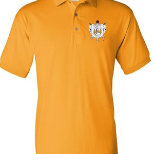 May include: A yellow polo shirt with a small embroidered crest on the left chest. The crest features a shield with the letters "ΣΤΡ" and the words "Founded 1913" in blue.