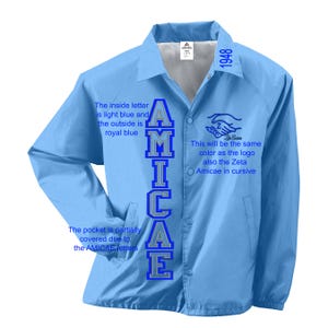 Peut inclure: Une veste bleu clair avec le mot "AMICAE" brodé sur le côté gauche en lettres bleues et grises. Le texte "This will be the same colour as the logo also the Zeta Amicae in cursive" est imprimé sur le côté droit de la veste.