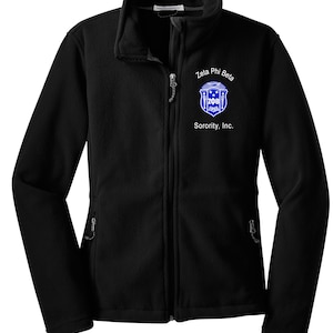 May include: Black fleece jacket with a full zipper and two side pockets. The jacket features the text "Zeta Phi Beta Sorority, Inc." and a blue and white emblem on the left chest.