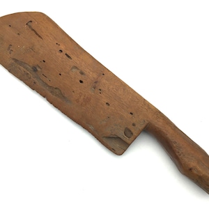 May include: A wooden knife with a brown handle and a blade that is worn and has a rough texture.