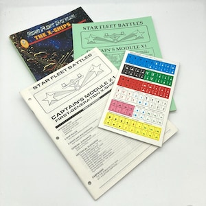 May include: A collection of Star Fleet Battles game materials, including rulebooks and ship charts. The books feature the game's title and images of starships. The color scheme includes blue, green, and white.