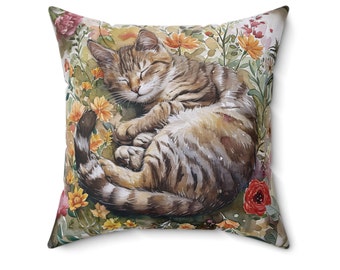 May include: A brown and tabby cat with green eyes is sleeping on a pillow with a floral pattern. The pillow is filled with watercolor flowers in shades of pink, yellow, orange, and green.