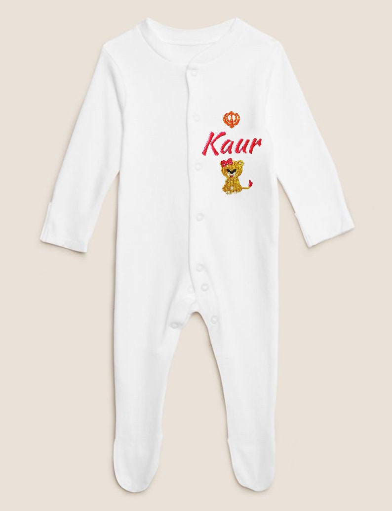 May include: White baby onesie with a pink lion and the name "Kaur" embroidered on the front.