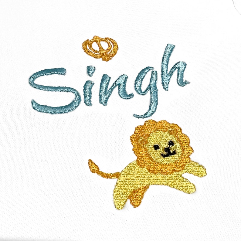 May include: A white onesie with blue embroidery that says "Singh" and a yellow embroidered lion with a crown above the name.