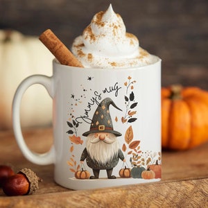 May include: White ceramic mug with a whimsical gnome design, the text "Jimmy's mug", and a whipped cream topping with a cinnamon stick. The mug is surrounded by pumpkins and fall foliage, perfect for autumn. The mug is 11 oz.