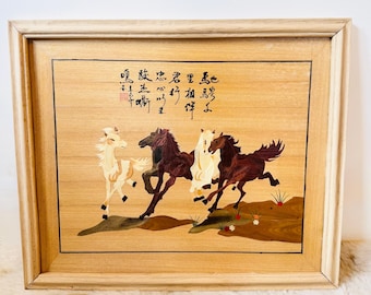 Puede incluir: Obra de arte enmarcada en madera con cuatro caballos en tonos marrón y crema, corriendo sobre un fondo marrón claro. La obra de arte incluye caligrafía china en la parte superior. El marco es de color madera clara.