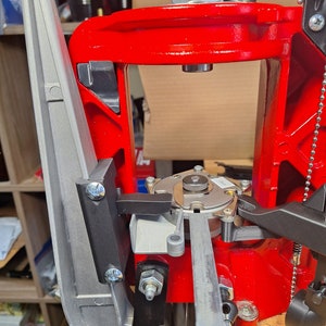 May include: A red reloading press with a silver lever and a black handle. The press has a silver metal plate with a small black lever on the right side.