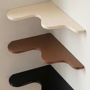 Puede incluir: Tres estanter&iacute;as de esquina en fila, cada una montada en una pared. La estanter&iacute;a superior es de color crema, la del medio es marr&oacute;n y la inferior es negra. Cada estanter&iacute;a tiene un dise&ntilde;o curvo &uacute;nico.