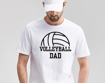 May include: White t-shirt with a black volleyball graphic and the text "Volleyball Dad" printed on the front.