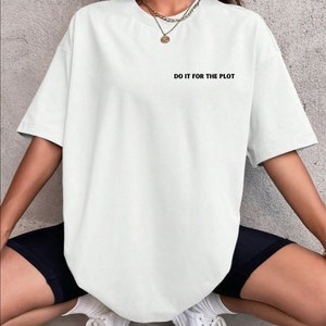 Puede incluir: Camiseta blanca de gran tamaño con mangas cortas y el texto "DO IT FOR THE PLOT" impreso en la parte delantera.
