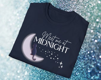 May include: A navy blue t-shirt featuring a white crescent moon with a black cat sitting on it. The text "Meet me at MIDNIGHT" is written in white on the shirt.