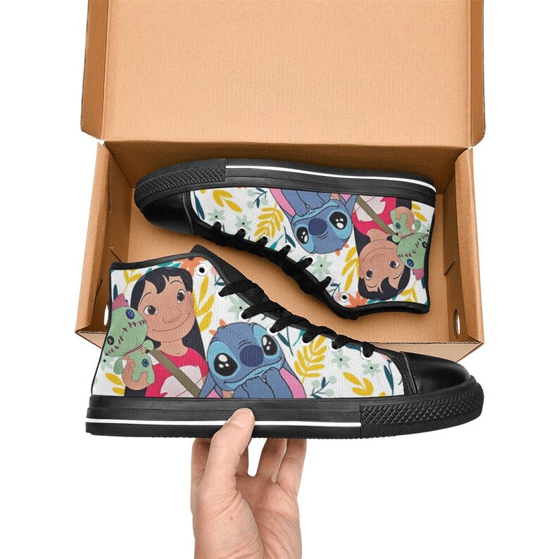 May include: High-top canvas sneakers featuring a colorful print of Lilo & Stitch characters. The shoes have black soles, laces, and toe caps. The design includes floral and leaf patterns on a white background.