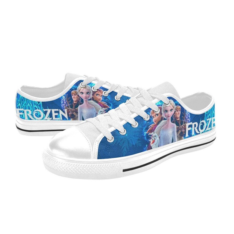 Puede incluir: Zapatillas bajas de lona blancas con un dise&ntilde;o azul y blanco con personajes de la pel&iacute;cula Frozen. Las palabras "Frozen" y "Froze" son visibles en los zapatos.