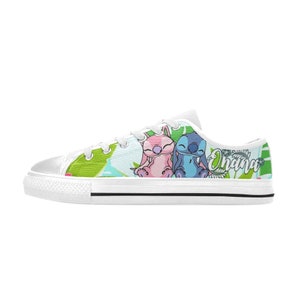 Puede incluir: Zapatillas bajas de lona blancas con un estampado colorido que presenta a Stitch y Angel de Lilo & Stitch. El estampado incluye hojas verdes, flores rosas y azules, y la palabra "Ohana".