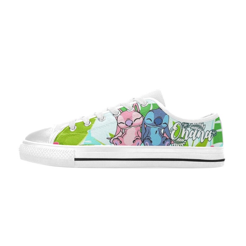 Puede incluir: Zapatillas bajas de lona blancas con un estampado colorido que presenta a Stitch y Angel de Lilo & Stitch. El estampado incluye hojas verdes, flores rosas y azules, y la palabra "Ohana".