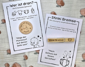 May include: Two cards with a wooden coin and a wooden clothespin. The coin is round and has the words "Wer ist dran?" and "Mama" on it. The clothespin has the words "Stinki Bremse" on it. The cards have text about baby care and odor control.