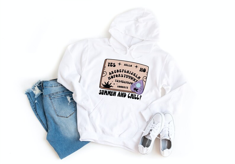 Pu&ograve; includere: Felpa con cappuccio bianca con una grafica di una tavola Ouija con il testo "Summon and Chill?" stampato su di essa.