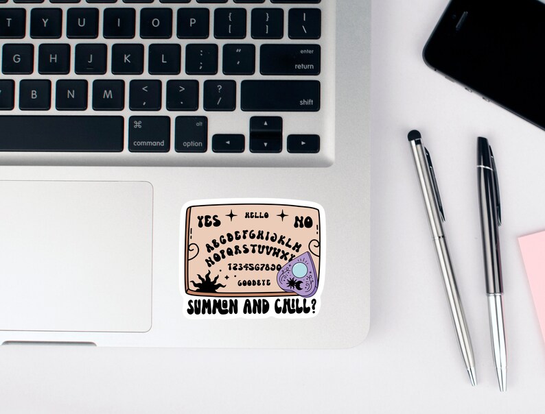 Pu&ograve; includere: Un adesivo di una tavola Ouija con il testo "SUMMON AND CHILL?" su un laptop.
